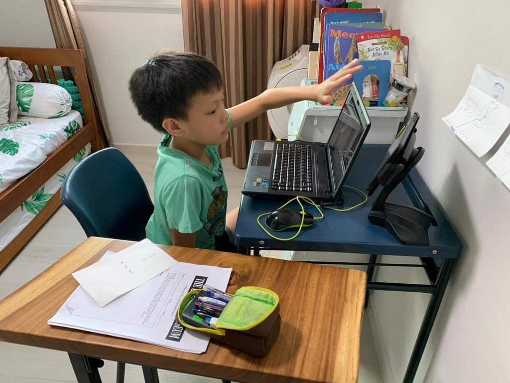 Boy in singapore learning online during home based learning on his computer