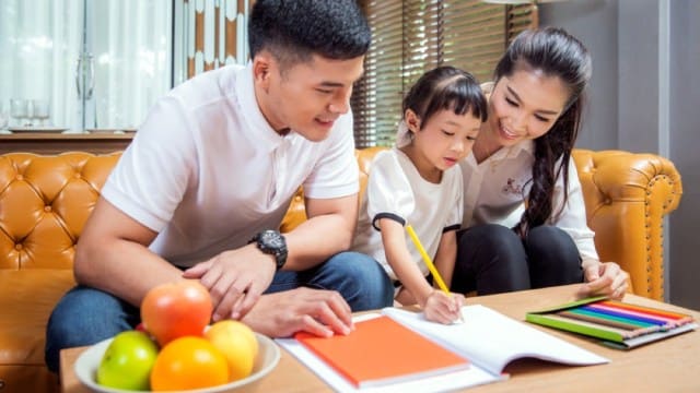 Singaporean parents planning their child's home learning timetable with her around