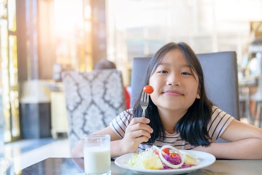 young-asian-girl-enjoying-her-meal-without-discomfort-or-reservation-due-to-removability-of-invisalign-aligners-compared-to-traditional-braces